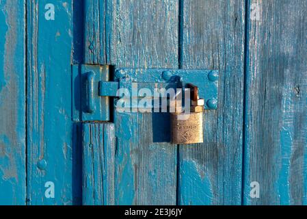 Wolmirstedt, Germania. 17 gennaio 2021. Un lucchetto dorato pende su una porta di legno blu. È fissato con quattro dadi in modo che non possa essere prelevato facilmente dai ladri. Credit: Stefano Nosini/dpa-Zentralbild/ZB/dpa/Alamy Live News Foto Stock