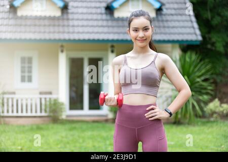 Istruttore di fitness femminile che si esercita con il piccolo manubri sul cortile. Foto Stock