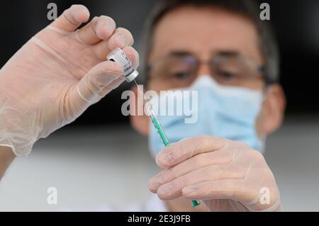 Pulsnitz, Germania. 19 gennaio 2021. Marcus Pohl, direttore medico della VAMED Clinic Schloss Pulsnitz, prepara il vaccino da Biontech/Pfizer per la vaccinazione di un'infermiera contro Corona. In considerazione dell'elevato numero di pazienti gravemente malati del Covid 19, gli ospedali della Sassonia sono ora sostenuti nelle loro cure da cliniche di riabilitazione. Nella fase attuale della pandemia, le strutture idonee sono state riconosciute come ospedale ausiliario dal Ministero della Salute e hanno assunto il riconoscimento dei pazienti: Robert Michael/dpa-Zentralbild/dpa/Alamy Live News Foto Stock