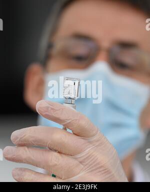 Pulsnitz, Germania. 19 gennaio 2021. Marcus Pohl, direttore medico della VAMED Clinic Schloss Pulsnitz, prepara il vaccino da Biontech/Pfizer per la vaccinazione di un'infermiera contro Corona. In considerazione dell'elevato numero di pazienti gravemente malati del Covid 19, gli ospedali della Sassonia sono ora sostenuti nelle loro cure da cliniche di riabilitazione. Nella fase attuale della pandemia, le strutture idonee sono state riconosciute come ospedale ausiliario dal Ministero della Salute e hanno assunto il riconoscimento dei pazienti: Robert Michael/dpa-Zentralbild/dpa/Alamy Live News Foto Stock