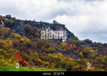 Vista panoramica della roccia per arrampicarsi contro una foresta di foglie autunnali, pietra di Bismantova, Reggio Emilia, Italia Foto Stock