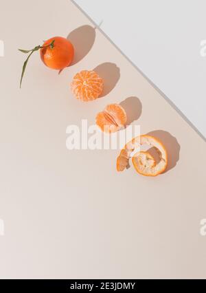 Sfondo creativo realizzato con nuovi tangerini su sfondo beige pastello. Estate frutta piatto Lay.Vertical orientamento. Foto Stock