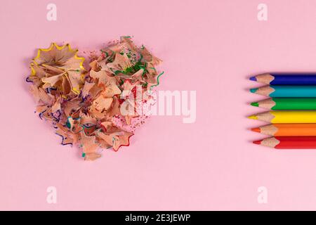 Matite colorate affilate e trucioli a forma di cuore. Decorazione per San Valentino. Matite arcobaleno o LGBT. Vista dall'alto Foto Stock