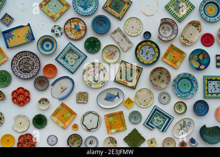 Molti piatti e ciotole diversi e colorati appesi sul parete Foto Stock