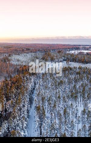 Neve coperta foresta invernale vista dal drone durante l'alba Foto Stock