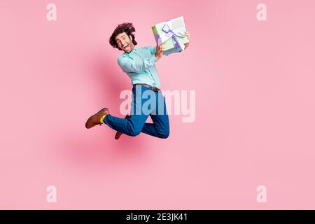 Ritratto fotografico a lunghezza intera dell'uomo felice che tiene presente avvolto box saltando su isolato su sfondo color rosa pastello Foto Stock