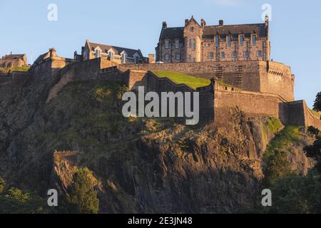 L'iconico Castello di Edimburgo arroccato sulla cima di Castlehill in una serata estiva come visto dai giardini di Princes Street. Foto Stock