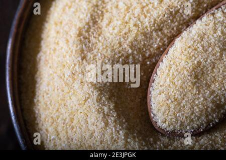 Farina di semola cruda non preparata, nota anche come polvere di Rava in ciotola. Semola cruda non preparata in ciotola e cucchiaio da vicino. Foto Stock