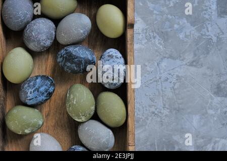 Vacanze di Pasqua. Uova di pasqua in marmo grigio, blu e verde in vassoio di legno su sfondo grigio cemento.Primavera festivo pasqua background.simbolo di Pasqua Foto Stock