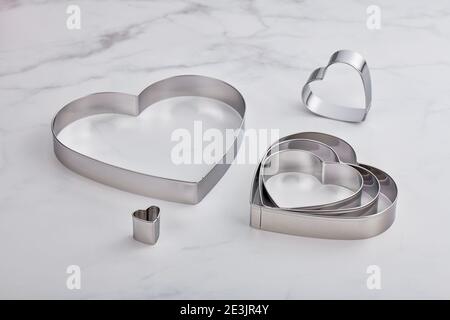 Set di tagliacinette a forma di cuore in acciaio inox su un bianco superficie in marmo Foto Stock