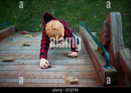 Vista ad occhio di uccello della parete di roccia di arrampicata del bambino sul playset in camice autunnale Foto Stock