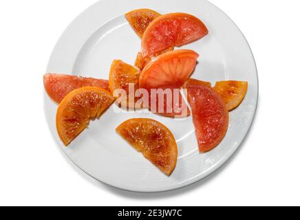 fette di frutta arancio cotte con cottura sous vide sotto vuoto, in piatto bianco isolato su sfondo bianco, vista dall'alto Foto Stock