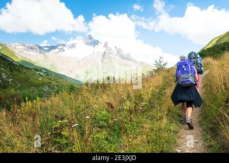 Giovane coppia escursioni nelle Alpi francesi in estate. L'Aiguille des Glaciers, montagna nel massiccio del Monte Bianco. Vista dalla valle di Chapieux, Savoia, Francia. Foto Stock