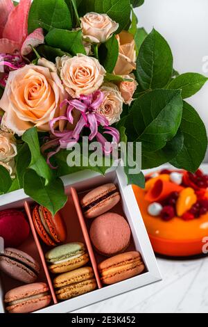 Compleanno fiori bouquet e arancio fiori, Mango, torta di frutta lamponi, macaron francesi caserecci colorati Foto Stock