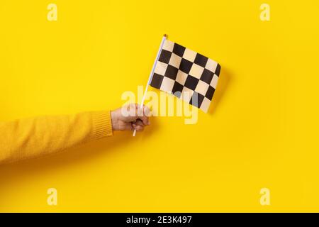 bandiera a scacchi in mano su sfondo giallo Foto Stock