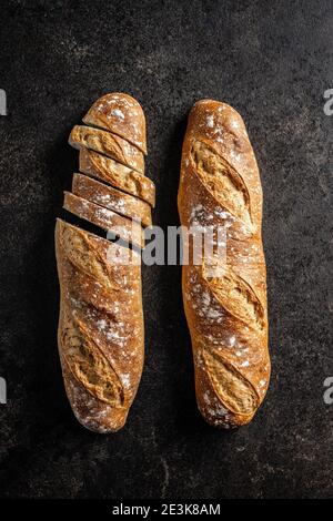 Baguette fresche croccanti. Baguette a fette su tavola nera. Vista dall'alto. Foto Stock