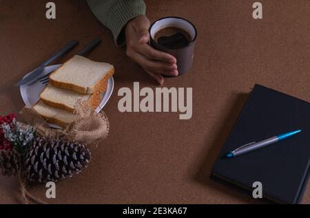 bere il caffè con il pane, creando nuove idee alla mia scrivania Foto Stock