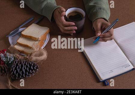 bere il caffè con il pane, creando nuove idee alla mia scrivania Foto Stock