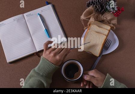bere il caffè con il pane, creando nuove idee alla mia scrivania Foto Stock
