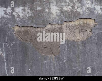 Un muro con pezzo caduto di gesso grigio e un ripetizione geometrica sotto di esso Foto Stock