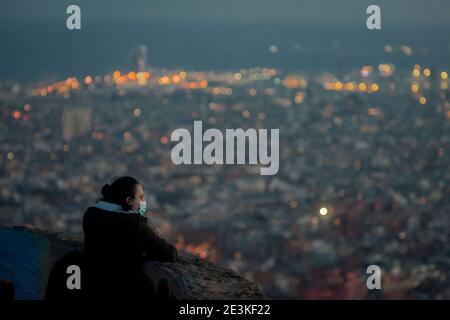 Una donna che indossa una maschera si affaccia sulla città di Barcellona dal punto di vista della collina di Turo de la Rovira. Foto Stock