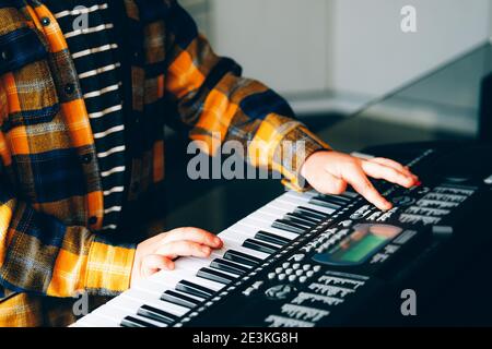 Primo piano delle mani del bambino che piange la tastiera elettrica del pianoforte dei bambini Foto Stock