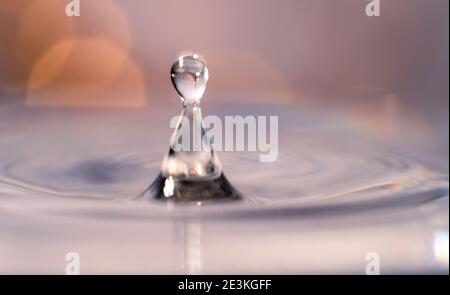 Primo piano di una goccia d'acqua e di uno sfondo a schizzi. Un piccolo impatto provoca grandi cambiamenti. Ondulazione, macro onda sulla superficie del liquido Foto Stock