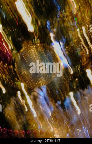 Riassunto - il panning diagonale produce striature di luce su dorati baubles su illuminato albero di Natale Foto Stock