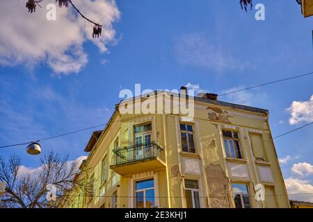 Vecchia casa di colore giallo e brownfield nella capitale Sofia con sfondo blu cielo. Foto Stock