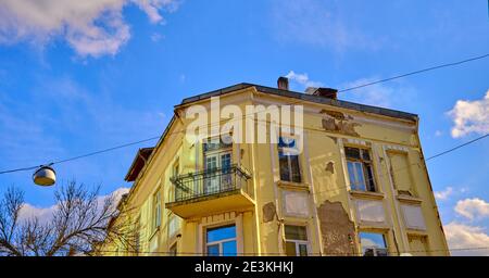 Vecchia casa di colore giallo e brownfield nella capitale Sofia con sfondo blu cielo. Foto Stock