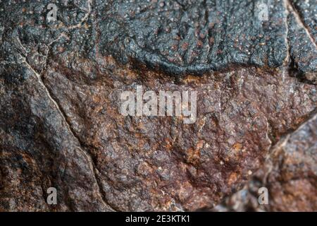 Macro foto della crosta di fusione da un meteorite condrita, pezzo di roccia formato nello spazio esterno nelle prime fasi del sistema solare come asteroidi. Foto Stock