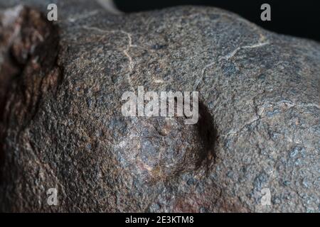 Macro foto della crosta di fusione da un meteorite condrita, pezzo di roccia formato nello spazio esterno nelle prime fasi del sistema solare come asteroidi. Foto Stock