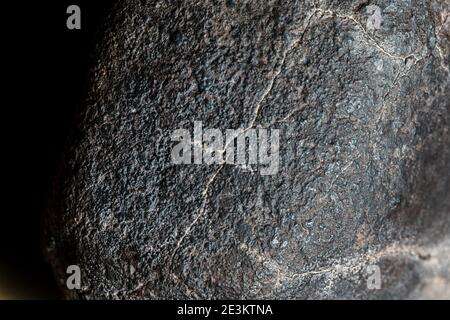 Macro foto della crosta di fusione da un meteorite condrita, pezzo di roccia formato nello spazio esterno nelle prime fasi del sistema solare come asteroidi. Foto Stock