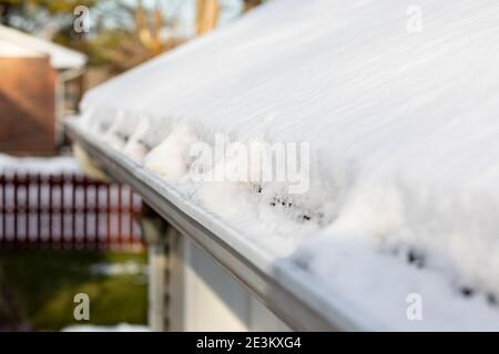 Grondaia del tetto piena di neve e ghiaccio dopo la tempesta invernale. Concetto di danni al tetto, manutenzione e riparazione domestica. Foto Stock