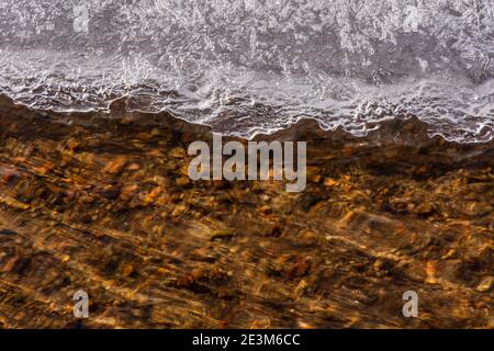 Uno strato di ghiaccio si è formato lungo il bordo del torrente con acqua fresca che scorre sotto il ghiaccio, Castle Rock Colorado USA. Foto scattata a dicembre. Foto Stock