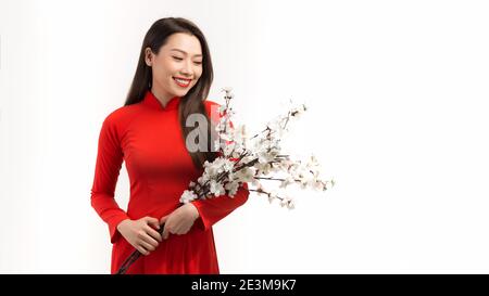 Belle donne asiatiche in rosso tradizionale abito vietnamita con tenuta ramo di fiori di pesca su sfondo bianco Foto Stock