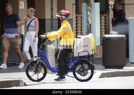 Un pilota di consegna di cibo EASI corre illegalmente sul marciapiede a Dixon Street, Chinatown a Sydney, NSW, Australia Foto Stock