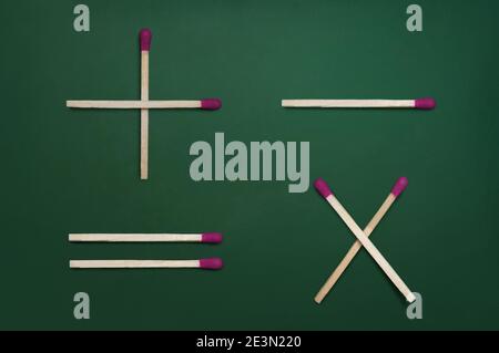 Simboli matematici di base - più, meno, moltiplicazione e uguale - sulla lavagna verde Foto Stock