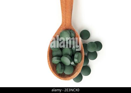 Vista dall'alto di un cucchiaio di legno con compresse di spirulina su bianco, un ritaglio di un cucchiaio di integratore di spirulina per una dieta sana Foto Stock