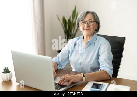 Donna anziana entusiasta che guarda la fotocamera Foto Stock