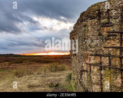 Un bunker a colonne della seconda guerra mondiale di tipo FW3 24, sdraiati sulla costa orientale dell'Inghilterra a Horsey, Norfolk, con il sole che tramonta sullo sfondo. Foto Stock