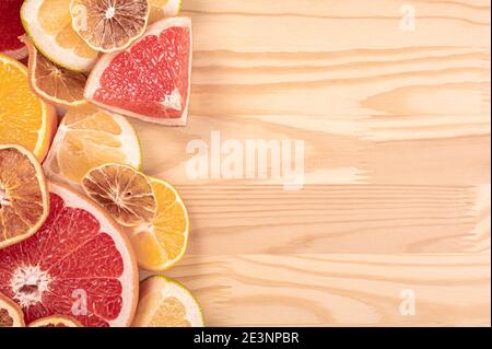 Agrumi su fondo ligneo, fette di agrumi tagliate e stese su tavola lignea. Arance limoni pompelmo Sweetie frutta fresca Foto Stock