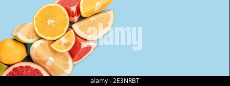 Banner estivo con limonata fredda con bordo ad angolo. Vista dall'alto su sfondo blu con spazio per la copia. Mescolare gli agrumi. Fette di arancia, pompelmo rosa e. Foto Stock