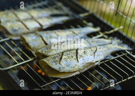 Preparare pesce fresco di trota su griglia di carbone per picnic estivo festa Foto Stock