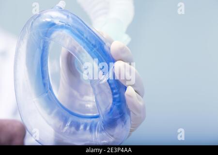 Il medico tiene il dispositivo di respirazione dell'aria sul viso del paziente durante la preparazione per l'intervento chirurgico. Foto Stock