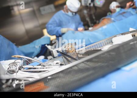 Strumenti chirurgici sterili nella capsula sullo sfondo dei chirurghi in funzione. Foto Stock