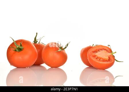 Quattro pomodori biologici succosi maturi rossi interi con coda di pontile verde e una metà di un pomodoro giacciono su uno sfondo bianco. Foto Stock