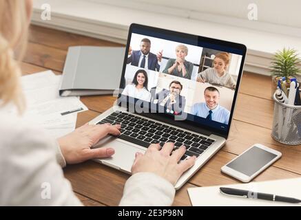 Donna d'affari che ha riunione con le persone di affari via il laptop al posto di lavoro Foto Stock