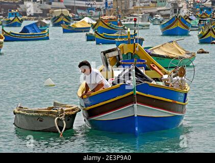 Pescatore maltese in una colorata barca da pesca maltese Foto Stock