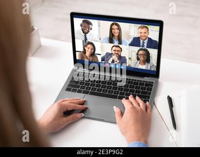 Donna al laptop con videochiamata incontro con i dipendenti al chiuso Foto Stock